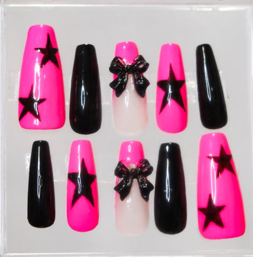Set of false nails with black stars and bows in pink, black, and white packaging.