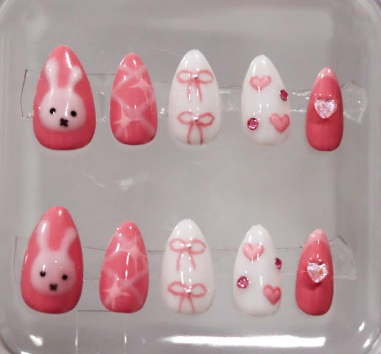 Set of pink and white nail art designs in a clear case.