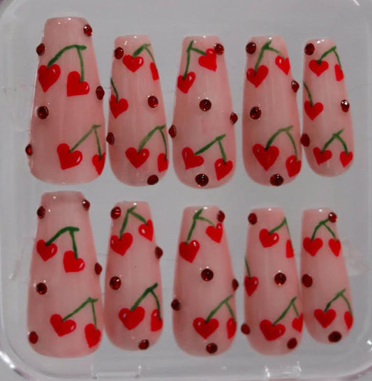 Nail art designs with cherries and hearts in a clear case.